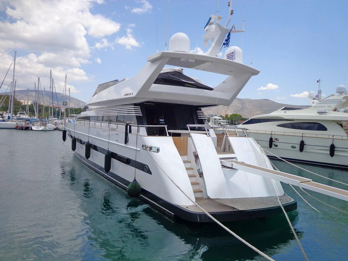A sleek and modern yacht is docked in a marina, showcasing its elegant design and spacious aft deck. aboard GALINI Yacht for Sale