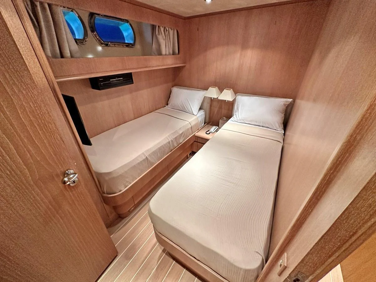 The twin stateroom features two single beds with a warm wooden finish and soft lighting. aboard GALINI Yacht for Sale