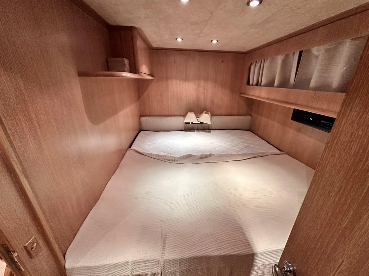 A cozy stateroom featuring a large bed and warm wooden paneling. aboard GALINI Yacht for Sale
