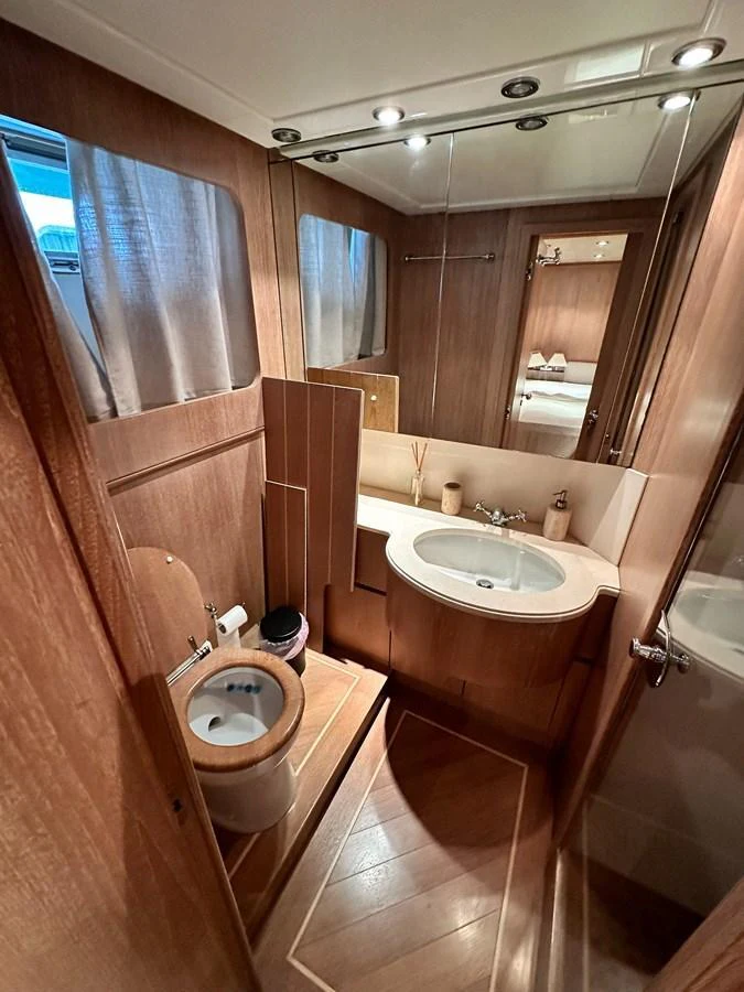A well-appointed yacht bathroom featuring a sink, toilet, and wooden cabinetry. aboard GALINI Yacht for Sale