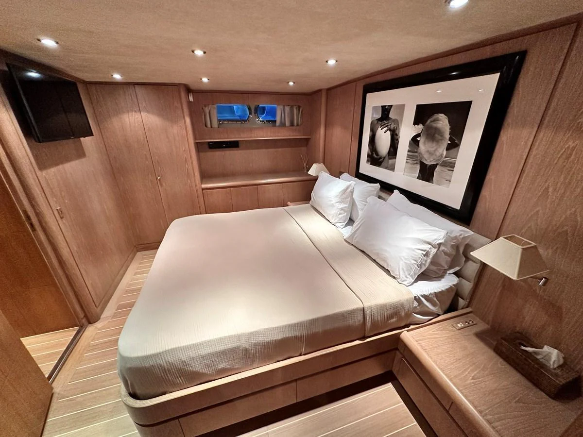 A cozy stateroom with a large bed and elegant wooden furnishings. aboard GALINI Yacht for Sale
