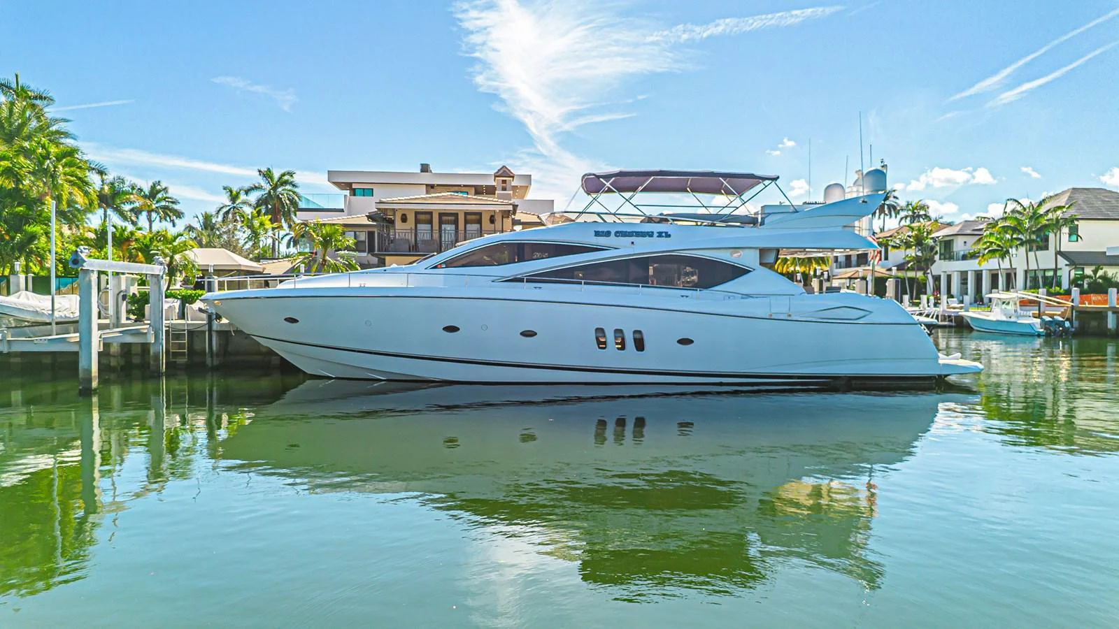 A sleek and modern yacht is docked in a serene marina, reflecting beautifully on the calm water. aboard BIG CHUBBY XL Yacht for Sale