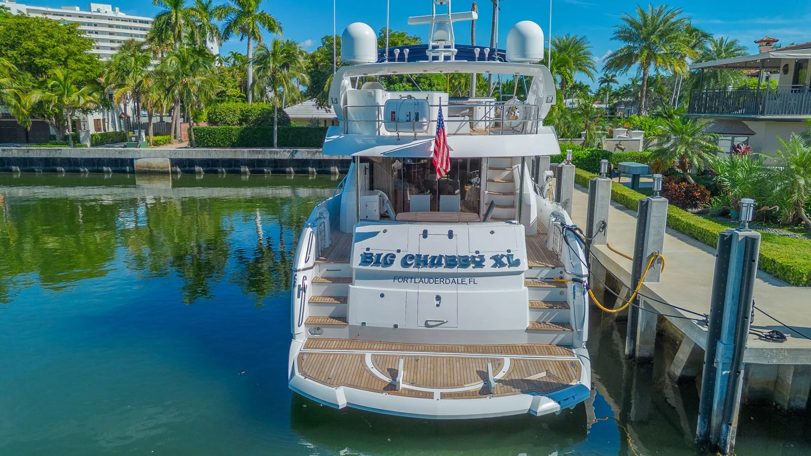 The yacht is docked in a serene marina, showcasing its spacious aft deck and elegant design. aboard BIG CHUBBY XL Yacht for Sale