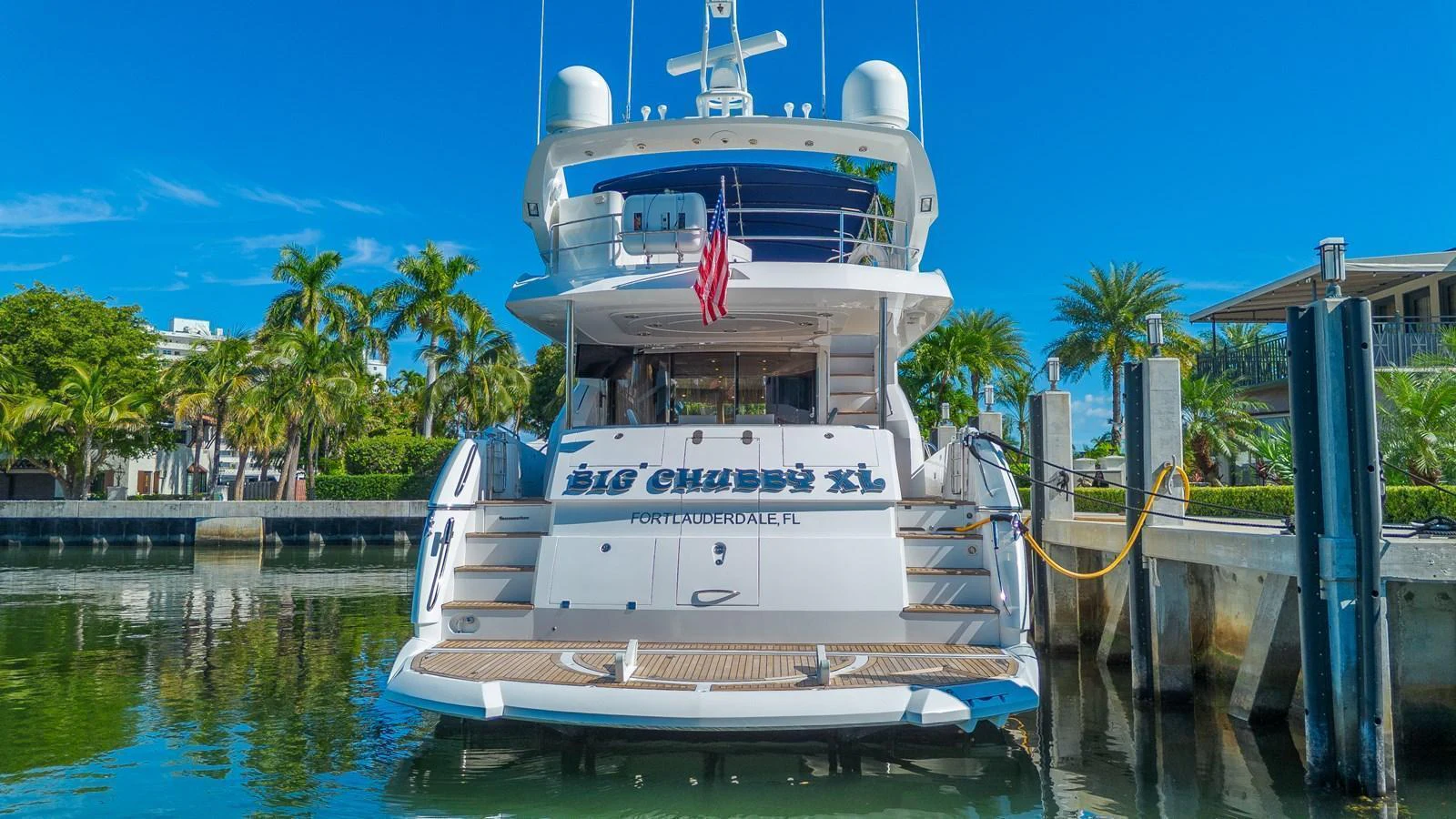 The yacht is docked at a marina, showcasing its spacious stern and inviting entryway. aboard BIG CHUBBY XL Yacht for Sale