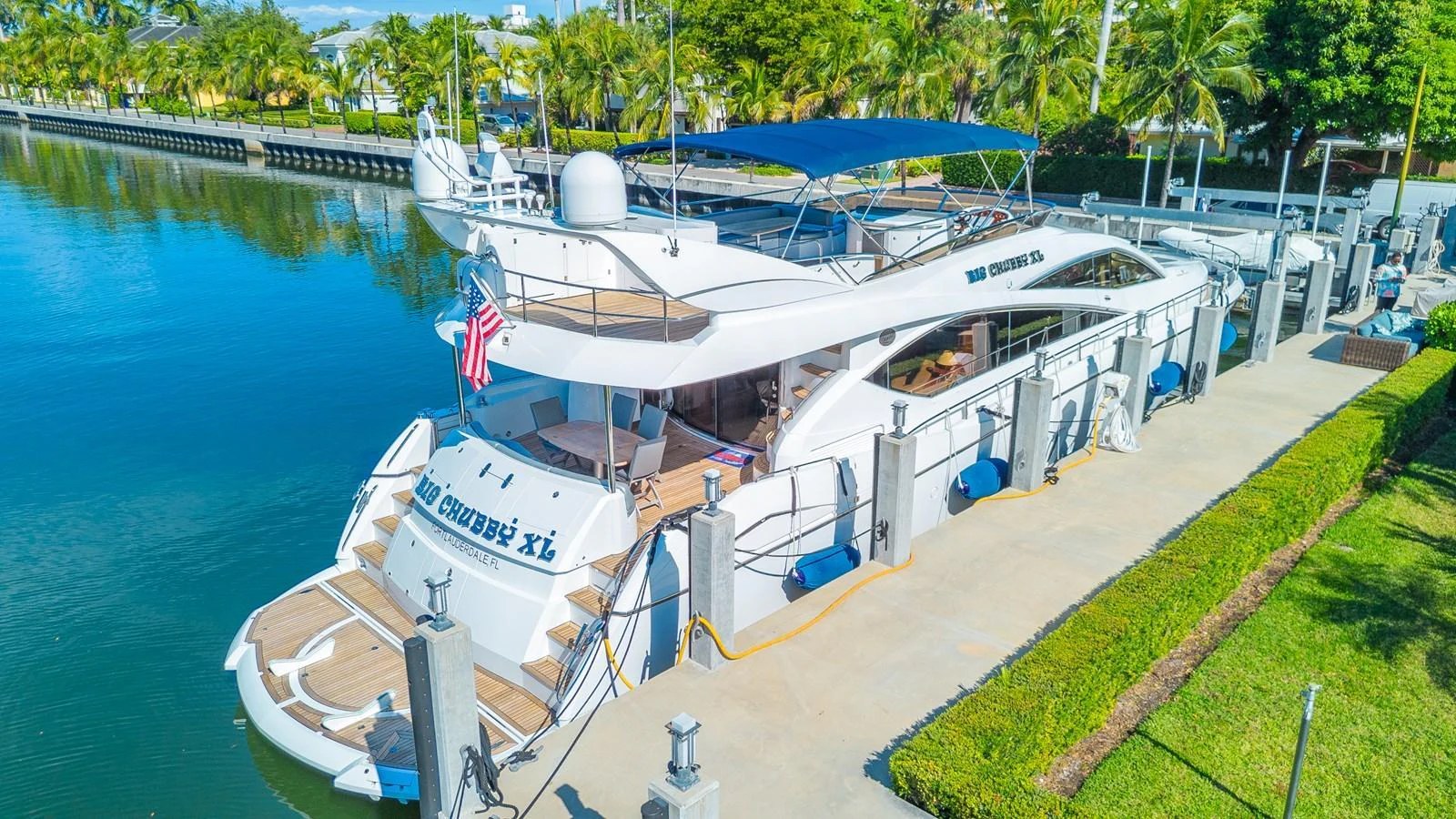 The yacht is docked at a marina, showcasing its spacious aft deck and sleek design. aboard BIG CHUBBY XL Yacht for Sale