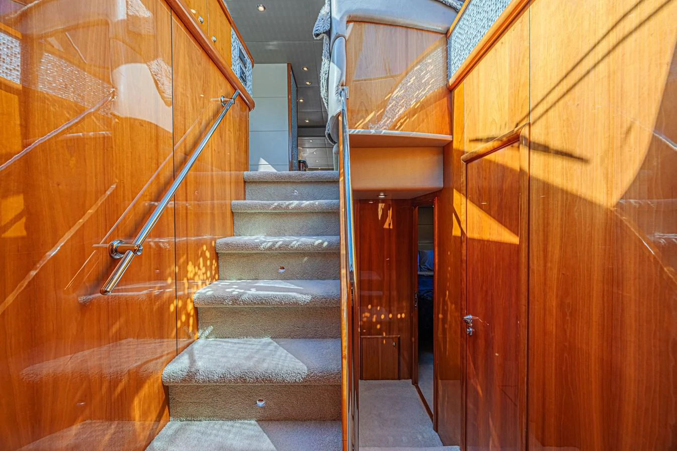 The image showcases a beautifully polished wooden staircase leading to the upper deck of the yacht. aboard BIG CHUBBY XL Yacht for Sale