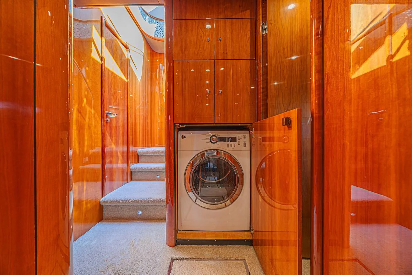 The yacht features a dedicated laundry area with a modern washing machine, surrounded by rich wooden cabinetry. aboard BIG CHUBBY XL Yacht for Sale
