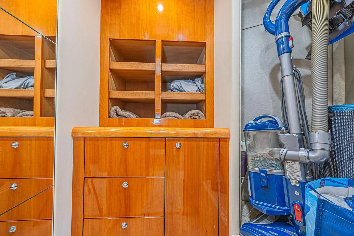 The image showcases a storage area with wooden cabinetry and cleaning equipment. aboard BIG CHUBBY XL Yacht for Sale