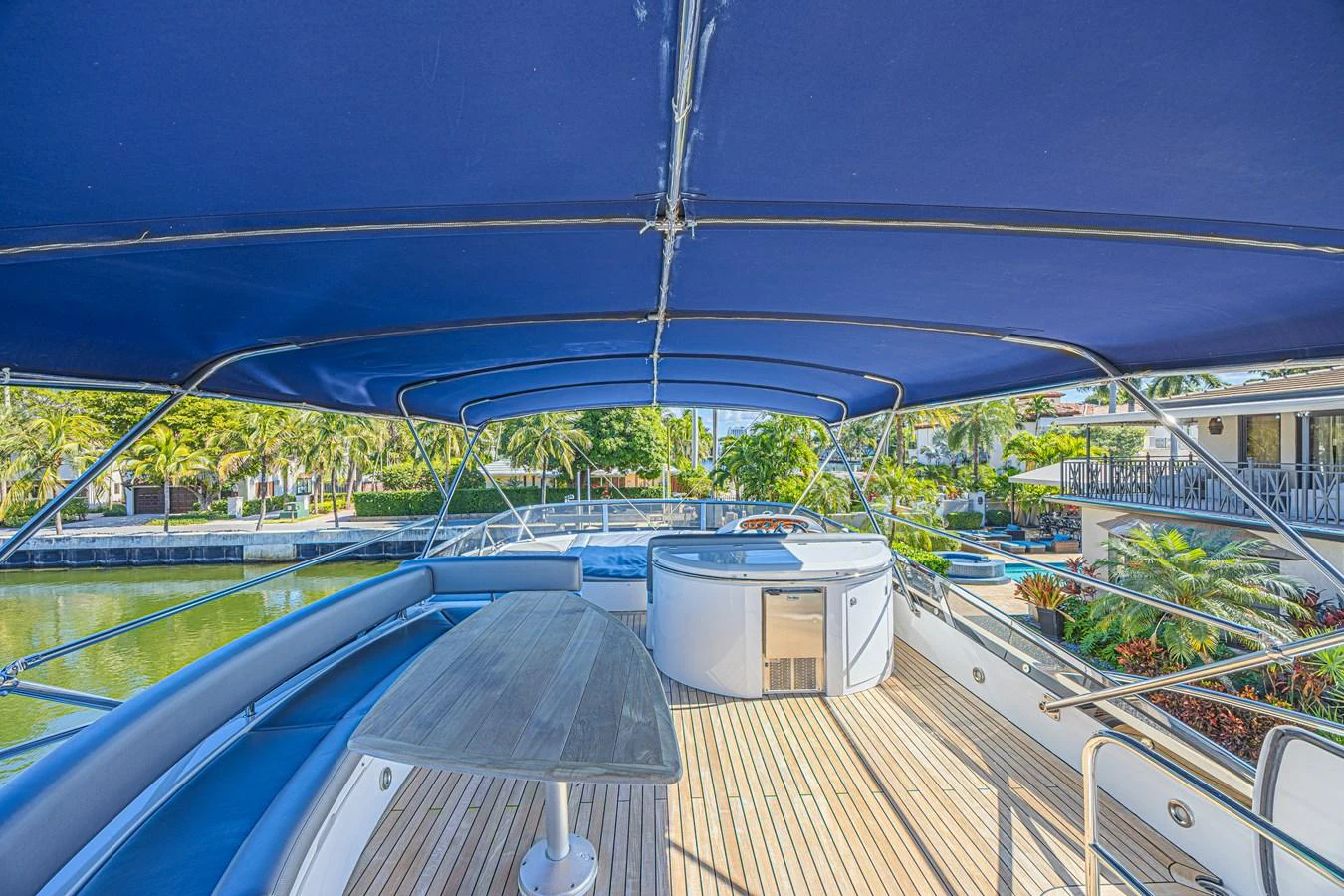 The flybridge offers a spacious seating area with a dining table and a hot tub under a blue canopy. aboard BIG CHUBBY XL Yacht for Sale