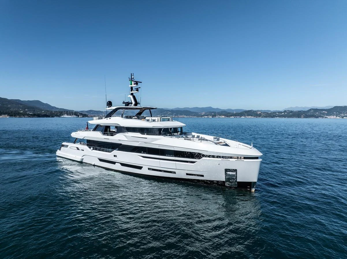 A sleek and modern yacht glides gracefully on calm waters with a scenic coastline in the background. aboard ANDALA Yacht for Sale