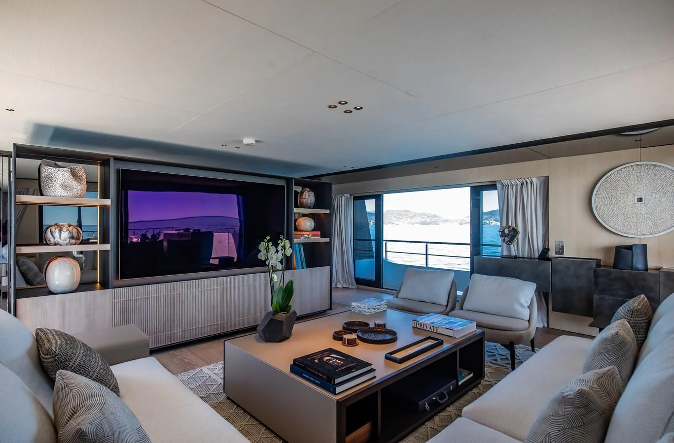 The salon features a spacious and elegantly designed seating area with a large TV and panoramic windows offering stunning sea views. aboard ANDALA Yacht for Sale