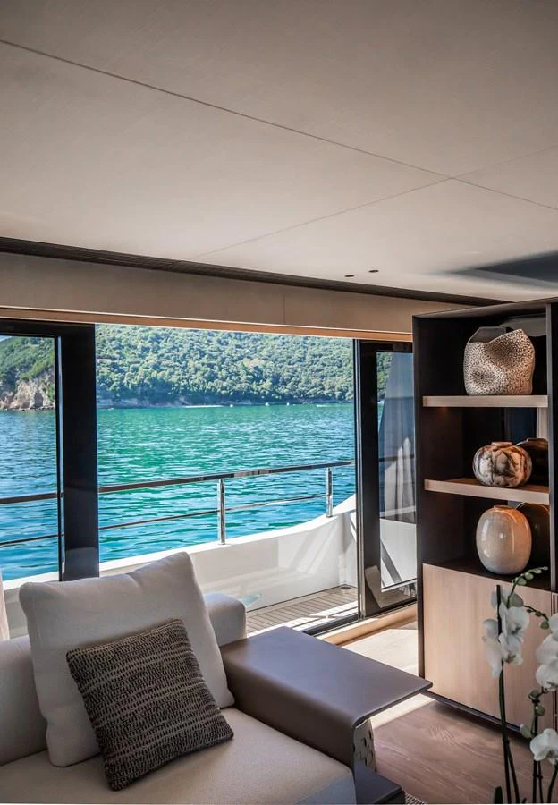 A serene interior space with a view of the water and lush greenery outside. aboard ANDALA Yacht for Sale