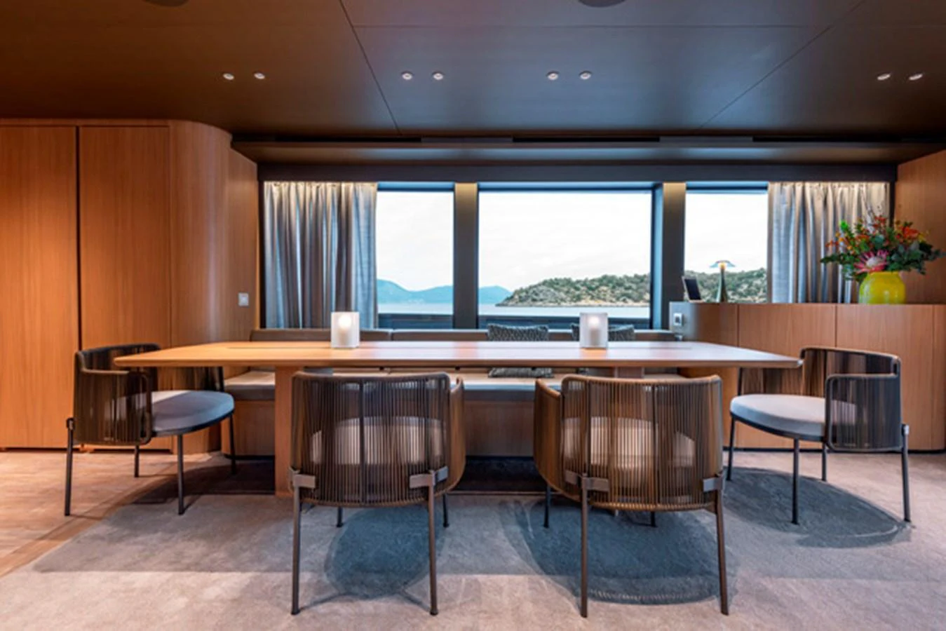 The yacht's dining area features a sleek wooden table with modern chairs and large windows offering stunning sea views. aboard FATSA Yacht for Sale