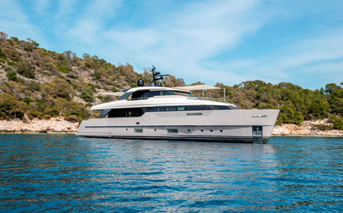 A sleek and modern yacht is anchored near a scenic coastline, showcasing its elegant design and spacious decks. aboard FATSA Yacht for Sale
