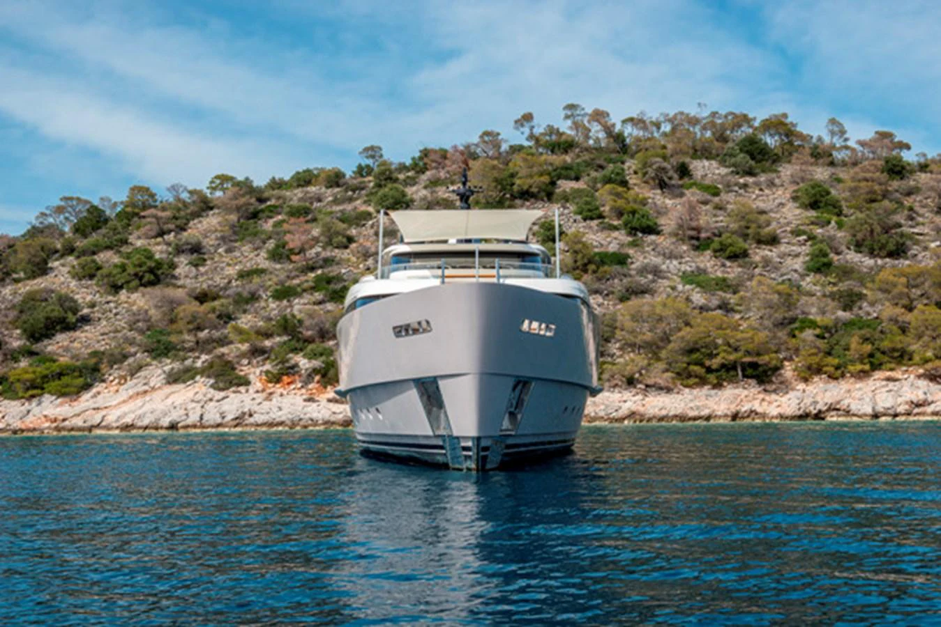 A luxurious yacht is anchored in a serene bay with a scenic hillside backdrop. aboard FATSA Yacht for Sale