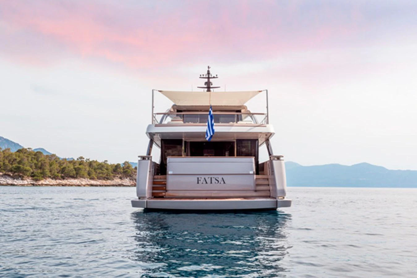 The yacht is shown from the rear, anchored in calm waters with a scenic backdrop. aboard FATSA Yacht for Sale