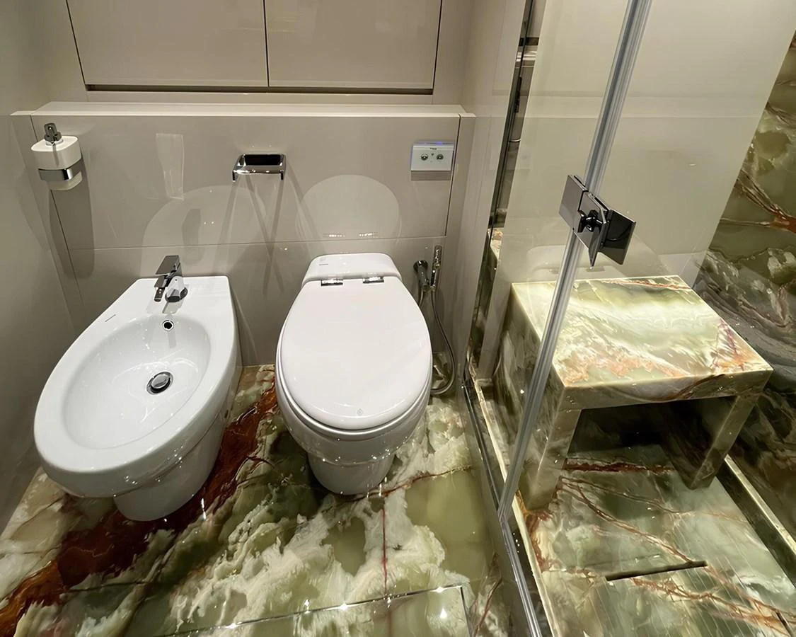 The yacht's bathroom features a modern design with a bidet and toilet, complemented by luxurious marble flooring. aboard LYDIA Yacht for Sale