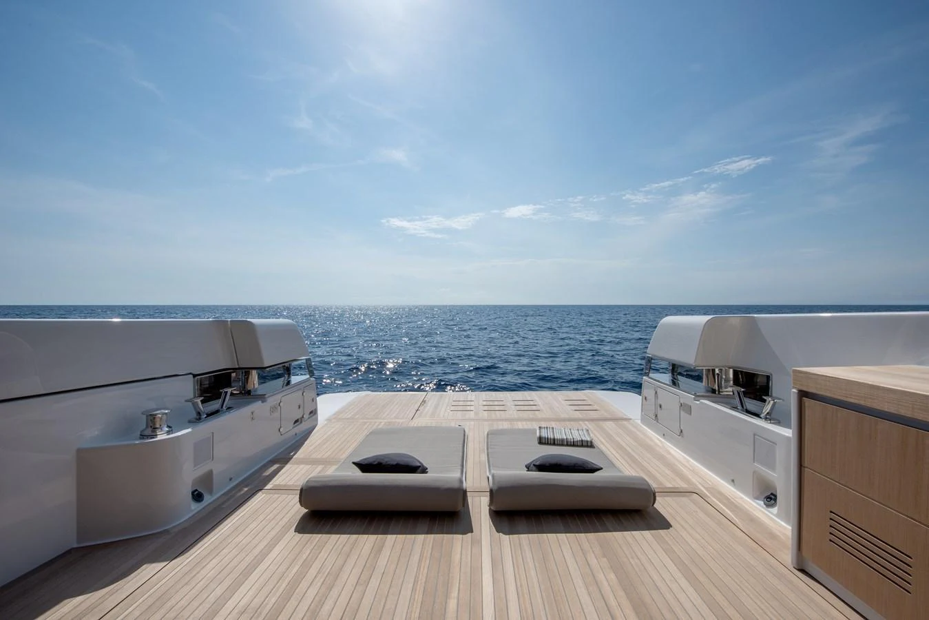 The aft deck features luxurious sun loungers with a stunning ocean view. aboard BLUEGAME BGX63 #49 Yacht for Sale