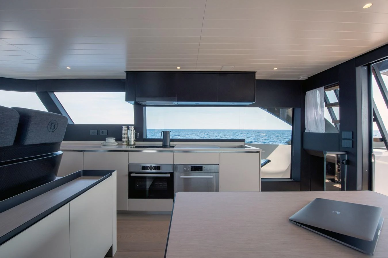 The yacht's modern galley features sleek cabinetry and state-of-the-art appliances with a stunning ocean view. aboard BLUEGAME BGX63 #49 Yacht for Sale