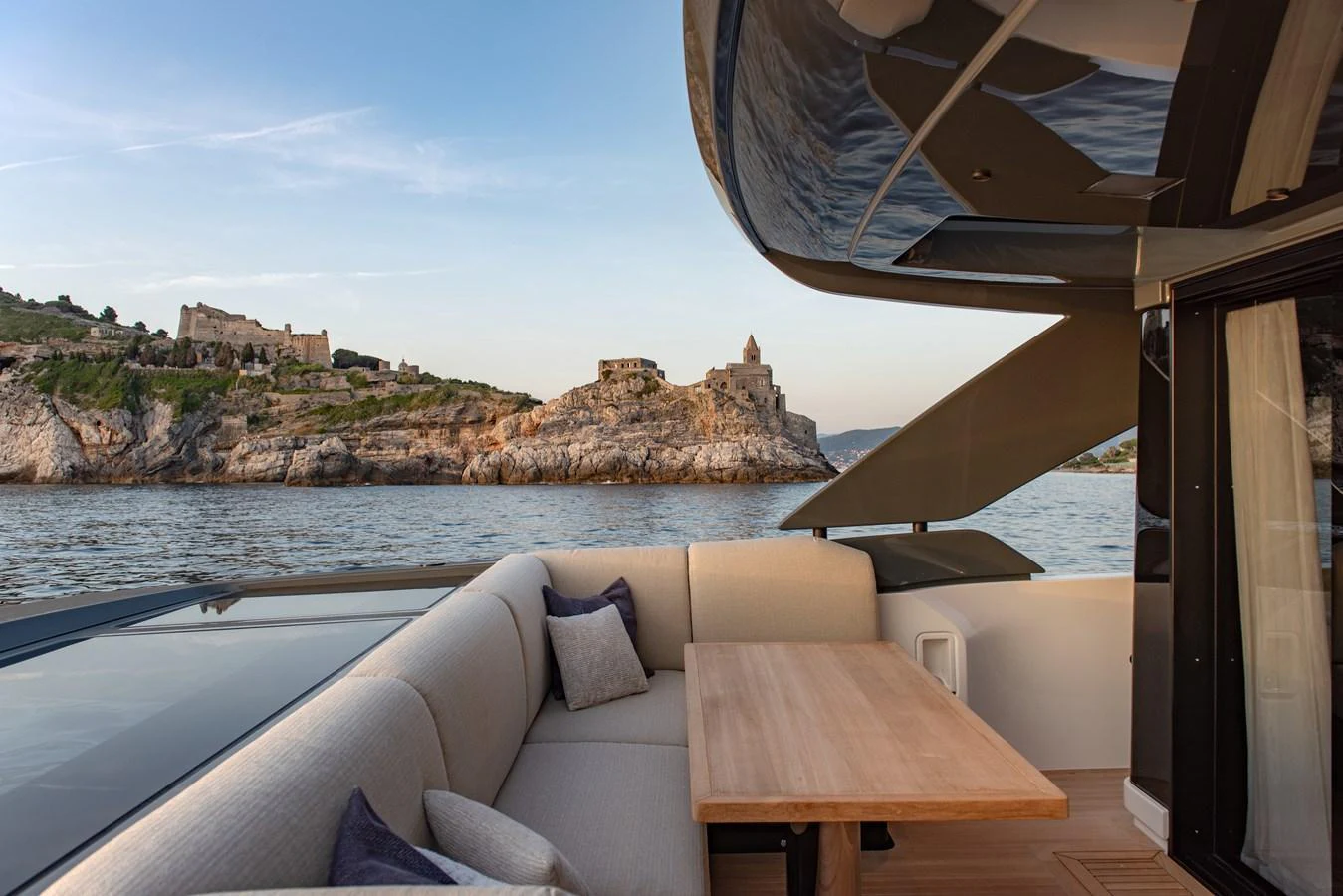 The aft deck offers a cozy seating area with a wooden table, perfect for enjoying scenic views. aboard BLUEGAME BGX63 #49 Yacht for Sale