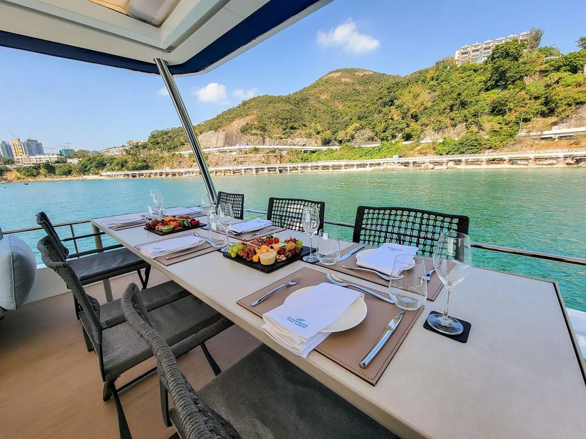 An elegant alfresco dining area set with fine tableware and a scenic view of the coastline. aboard LAGOON SIXTY 7 Yacht for Sale