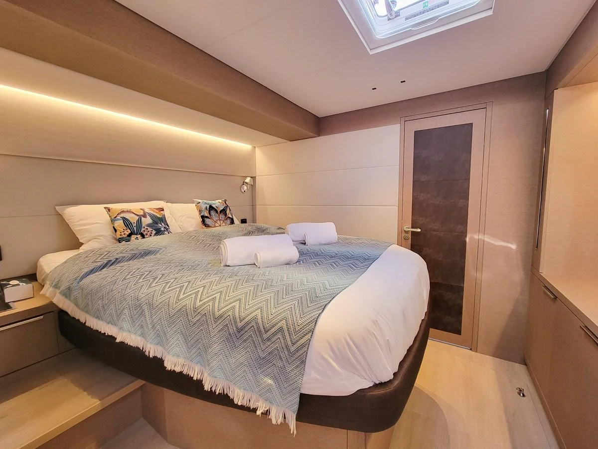 The stateroom features a cozy bed with elegant bedding and soft lighting, creating a warm and inviting atmosphere. aboard LAGOON SIXTY 7 Yacht for Sale