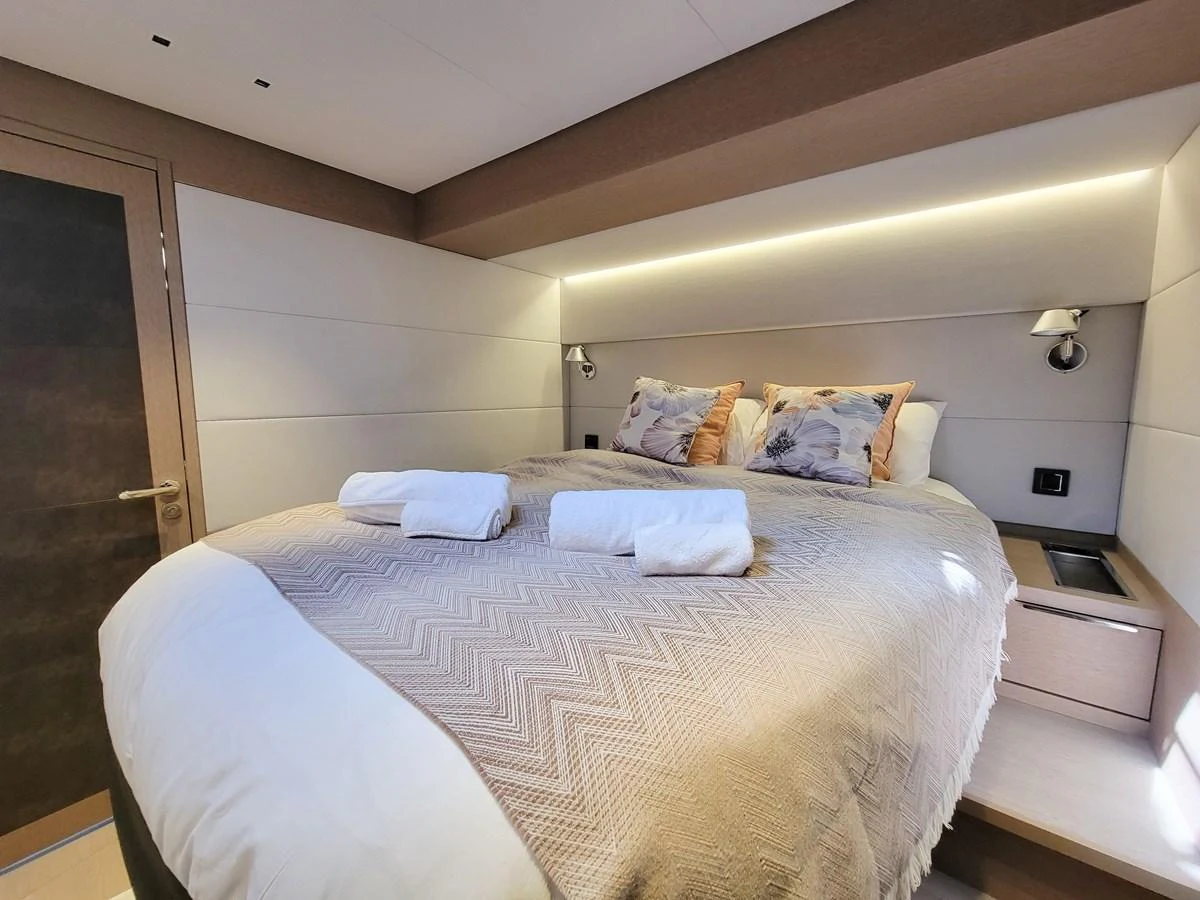 A cozy stateroom featuring a neatly made bed with soft lighting. aboard LAGOON SIXTY 7 Yacht for Sale