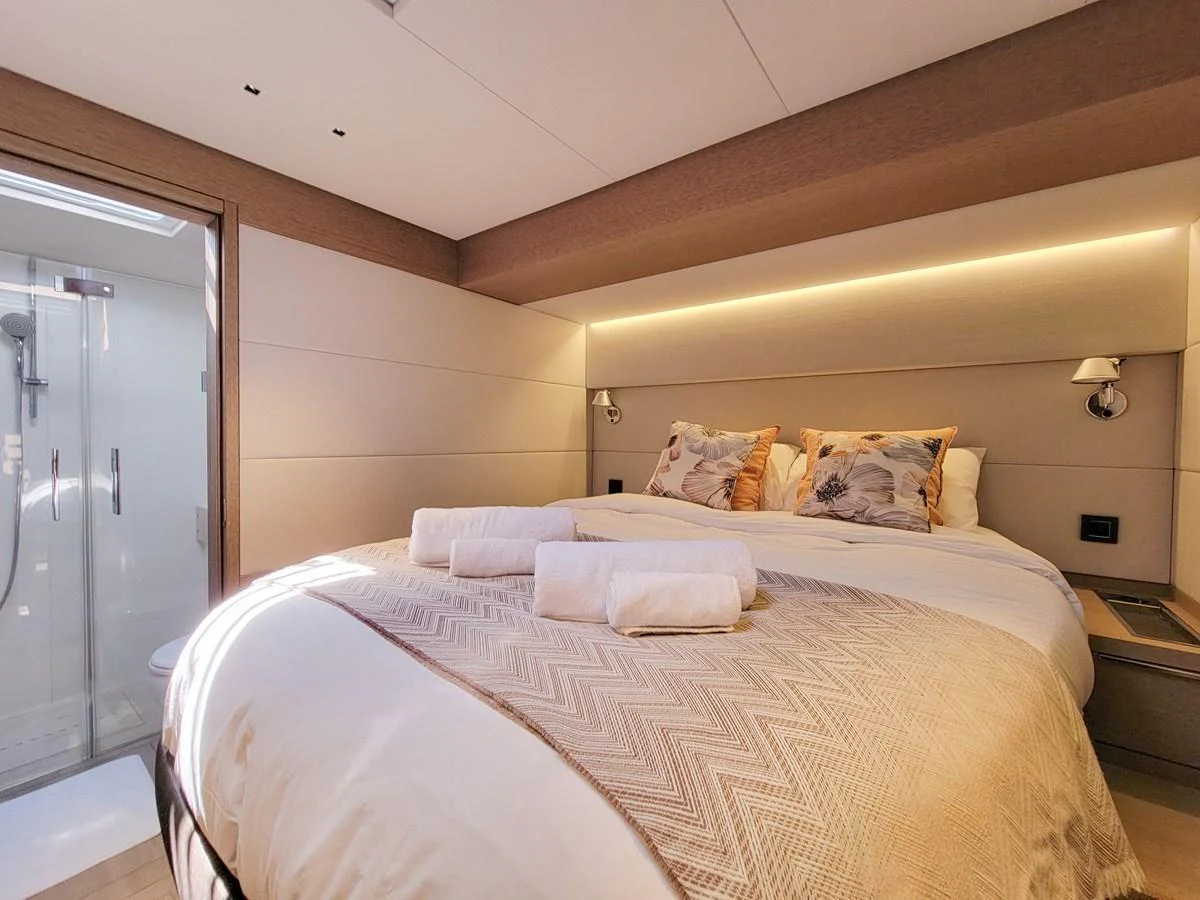 A cozy stateroom featuring a comfortable bed and an adjacent en-suite bathroom. aboard LAGOON SIXTY 7 Yacht for Sale