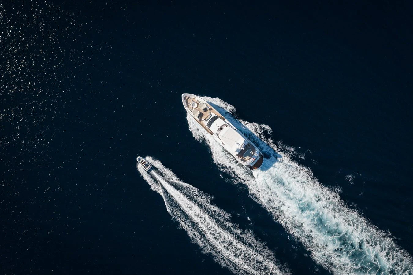 Aerial view of a luxurious yacht cruising through deep blue waters with a tender following closely behind. aboard KING POWER Yacht for Sale