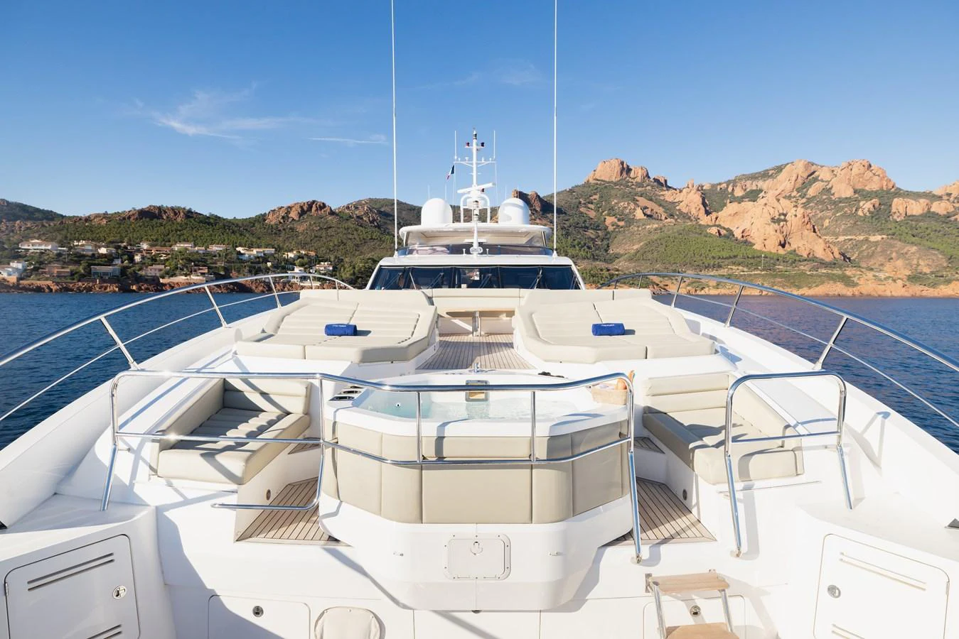 The yacht's bow features luxurious sun loungers and a jacuzzi, set against a stunning coastal backdrop. aboard KING POWER Yacht for Sale