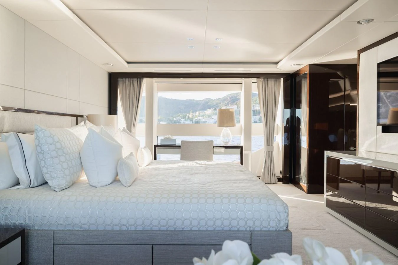 The master stateroom features a luxurious bed with a scenic view through large windows. aboard KING POWER Yacht for Sale
