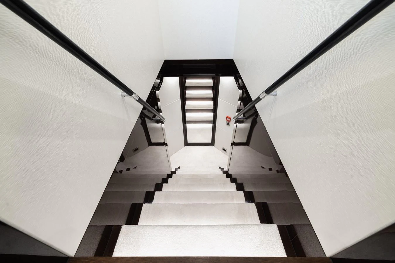 A sleek and modern staircase with dark railings and light steps leads to the lower deck. aboard KING POWER Yacht for Sale