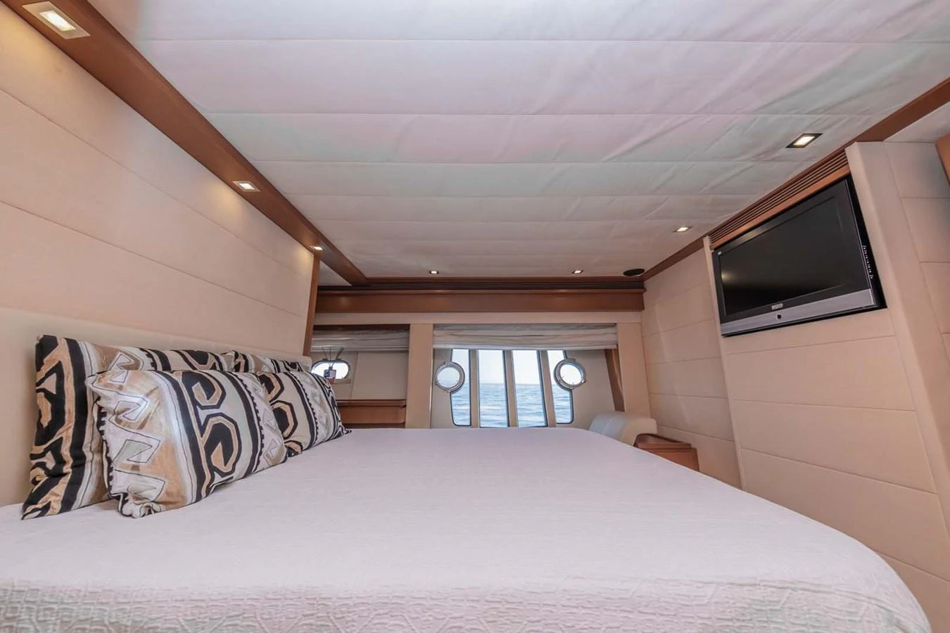 a bed with a white sheet and a television on the wall aboard STELLINA Yacht for Sale