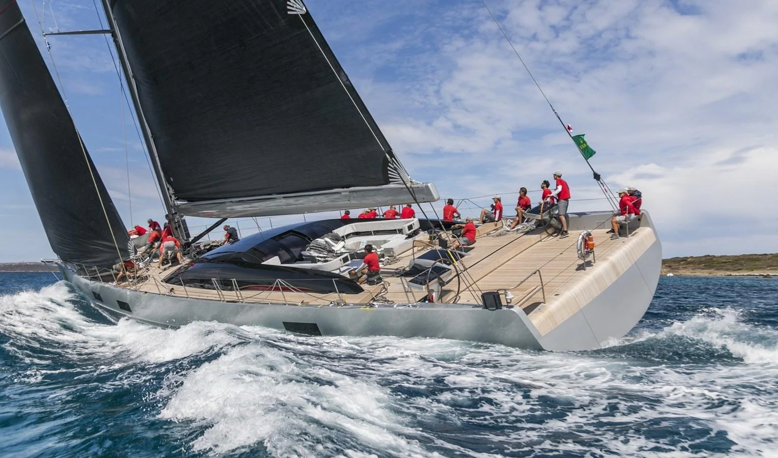 A sleek sailing yacht glides through the water with its crew actively engaged on deck. aboard ANOMALY Yacht for Sale