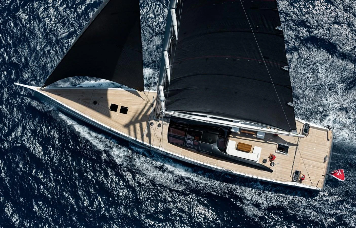 A sleek sailing yacht glides through the open sea, showcasing its elegant design and black sails. aboard ANOMALY Yacht for Sale