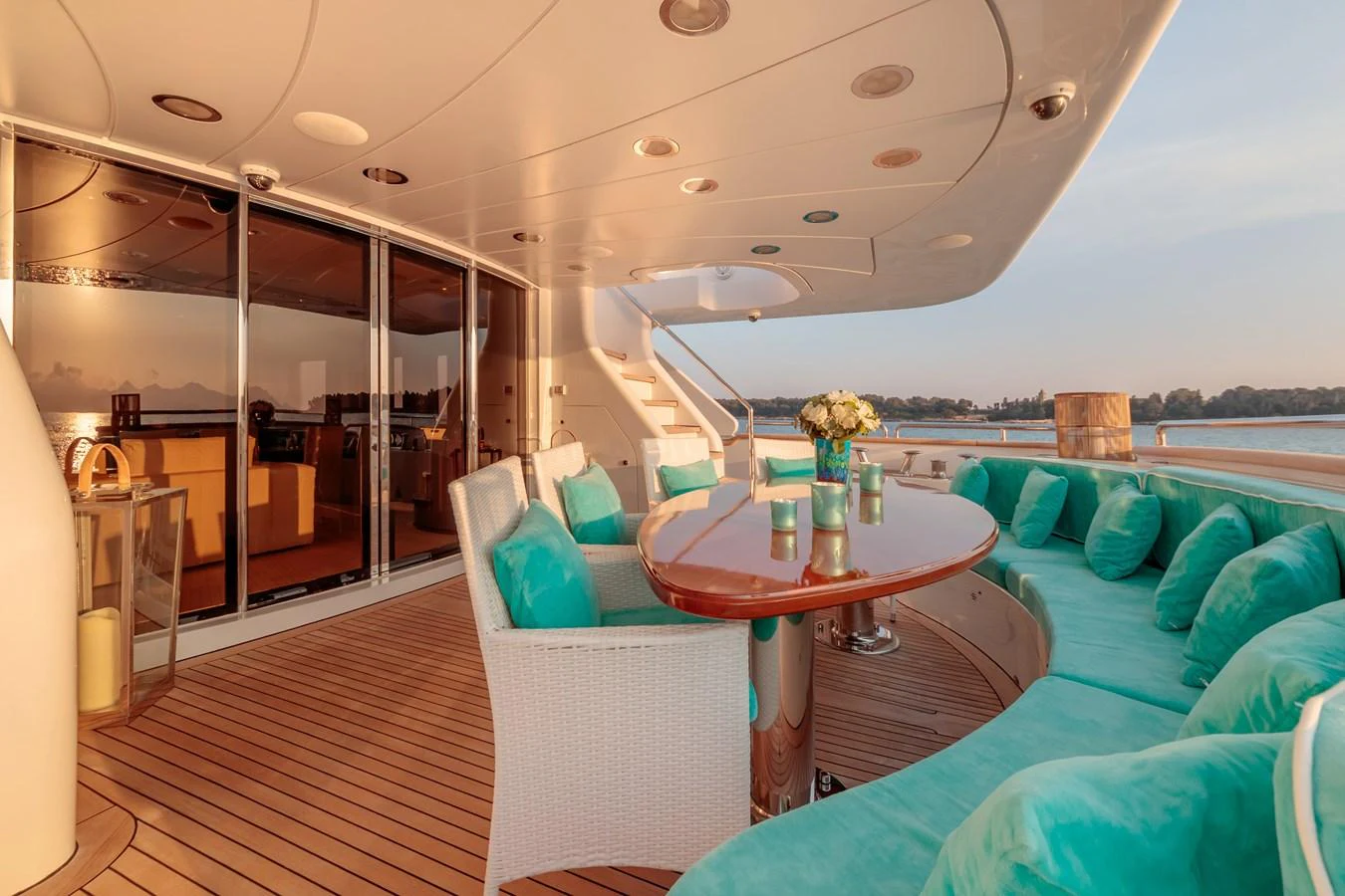 The aft deck features a spacious seating area with turquoise cushions and a dining table, perfect for enjoying meals with a view. aboard BANG! Yacht for Sale