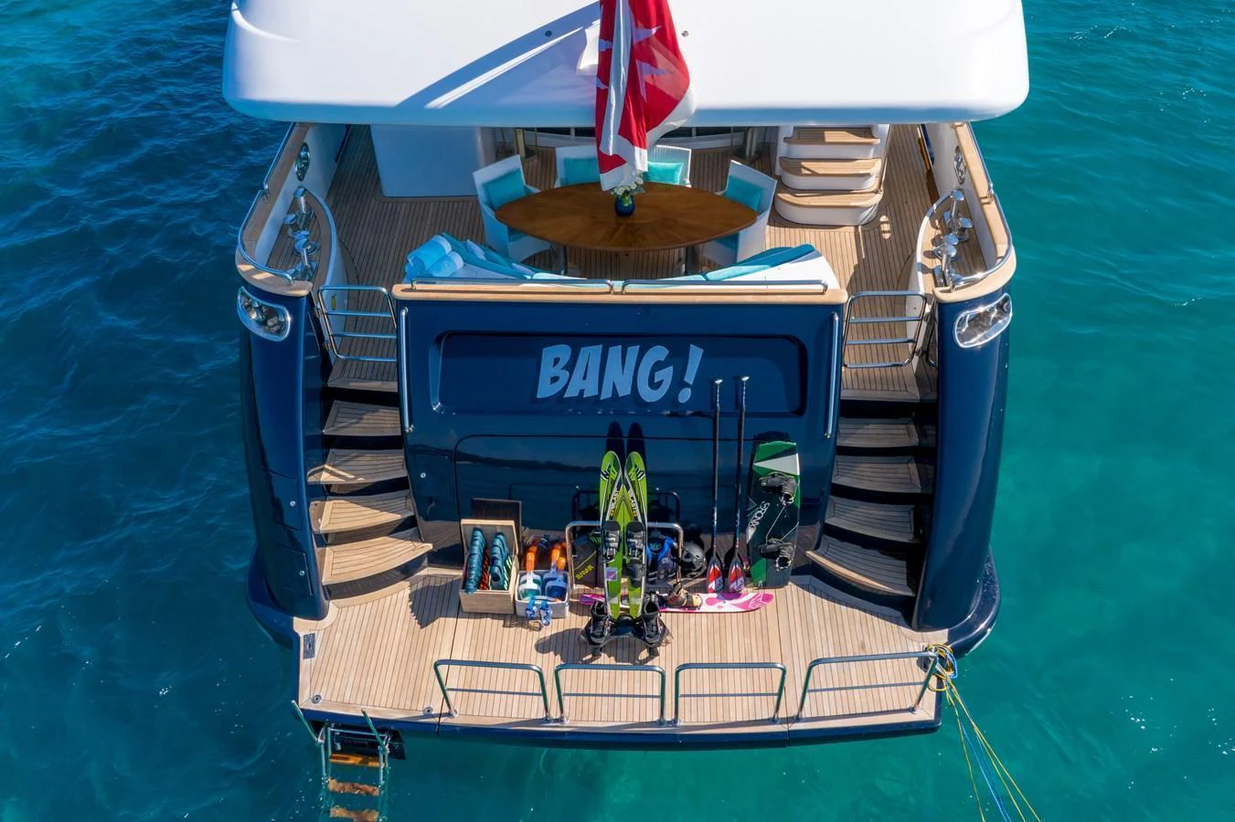 The aft deck of this yacht features a variety of water sports equipment, ready for adventure on the clear blue sea. aboard BANG! Yacht for Sale