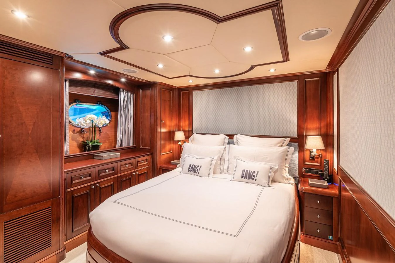 A luxurious stateroom featuring rich wood paneling and elegant bedding. aboard BANG! Yacht for Sale