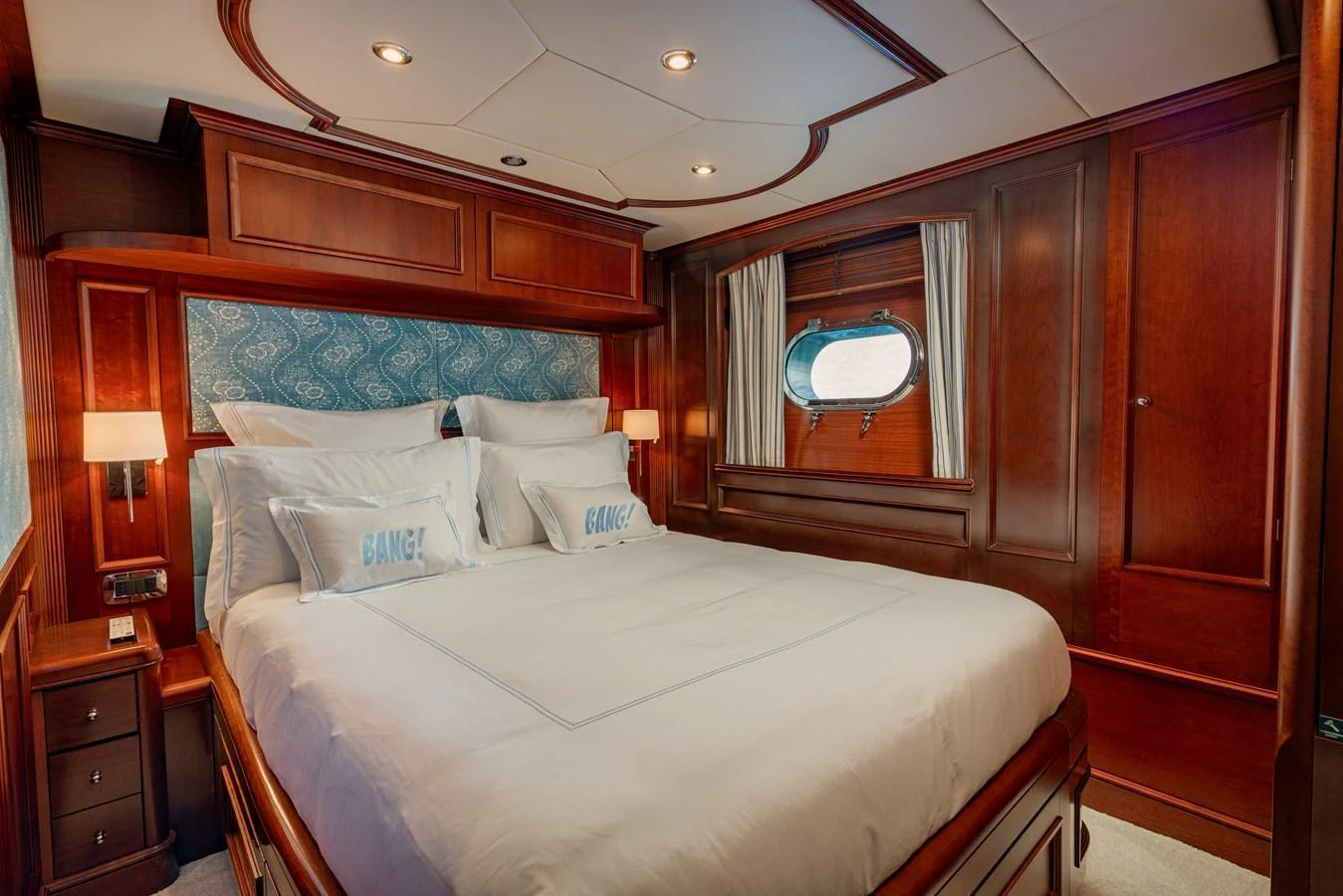 A luxurious stateroom featuring rich wood paneling and a comfortable bed with elegant bedding. aboard BANG! Yacht for Sale