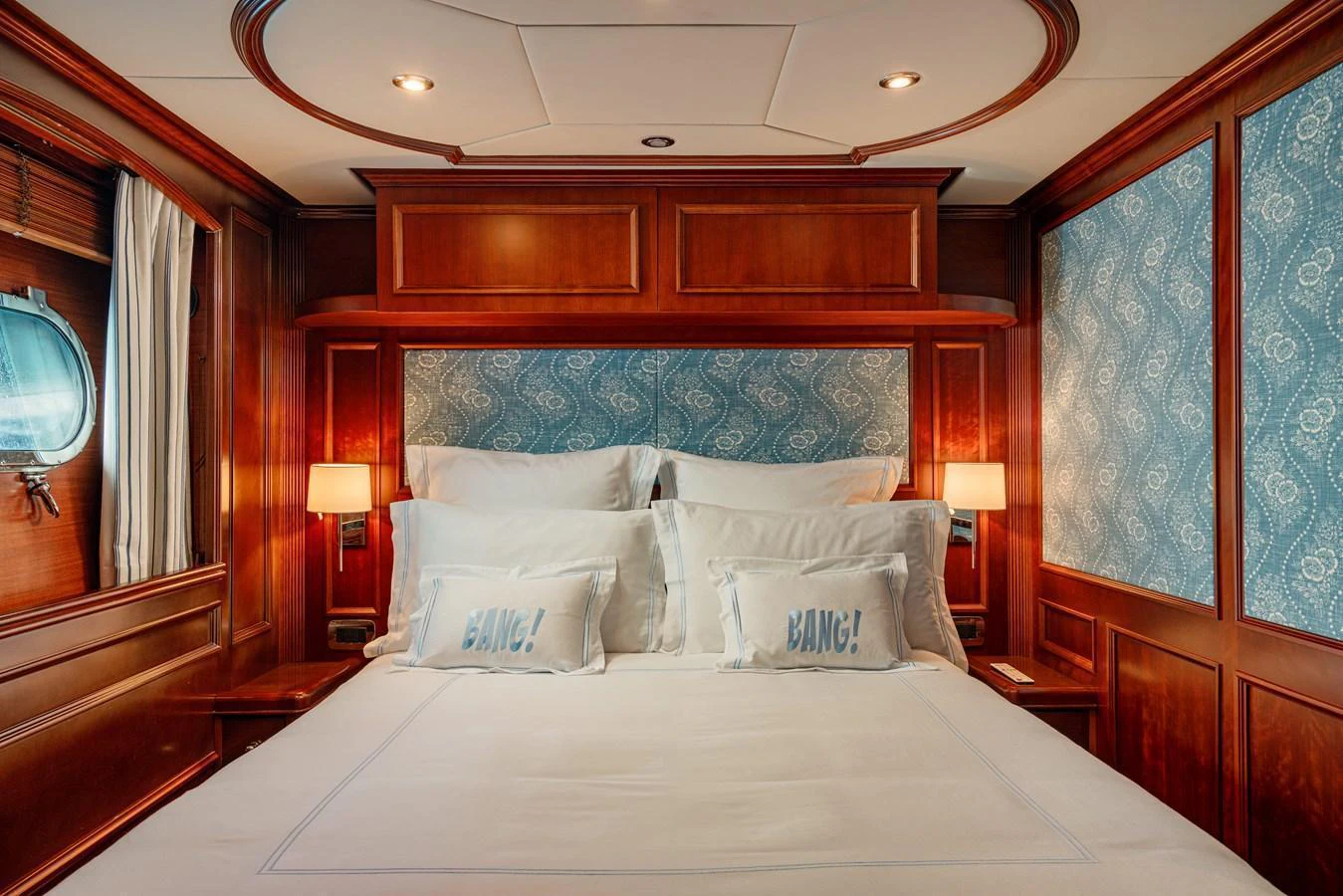 A luxurious stateroom featuring elegant wood paneling and plush bedding. aboard BANG! Yacht for Sale