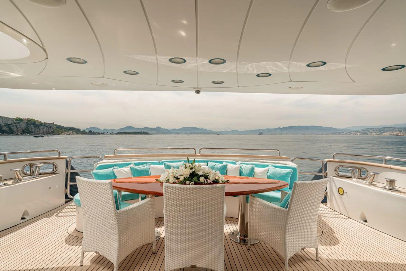 The aft deck features an elegant dining area with a round table and comfortable seating, offering stunning views of the surrounding waters. aboard BANG! Yacht for Sale