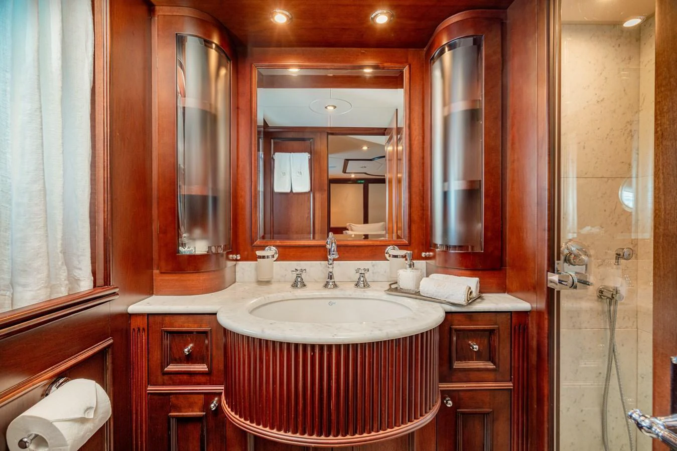 The yacht's bathroom features elegant wooden cabinetry and a marble countertop, creating a luxurious and inviting space. aboard BANG! Yacht for Sale