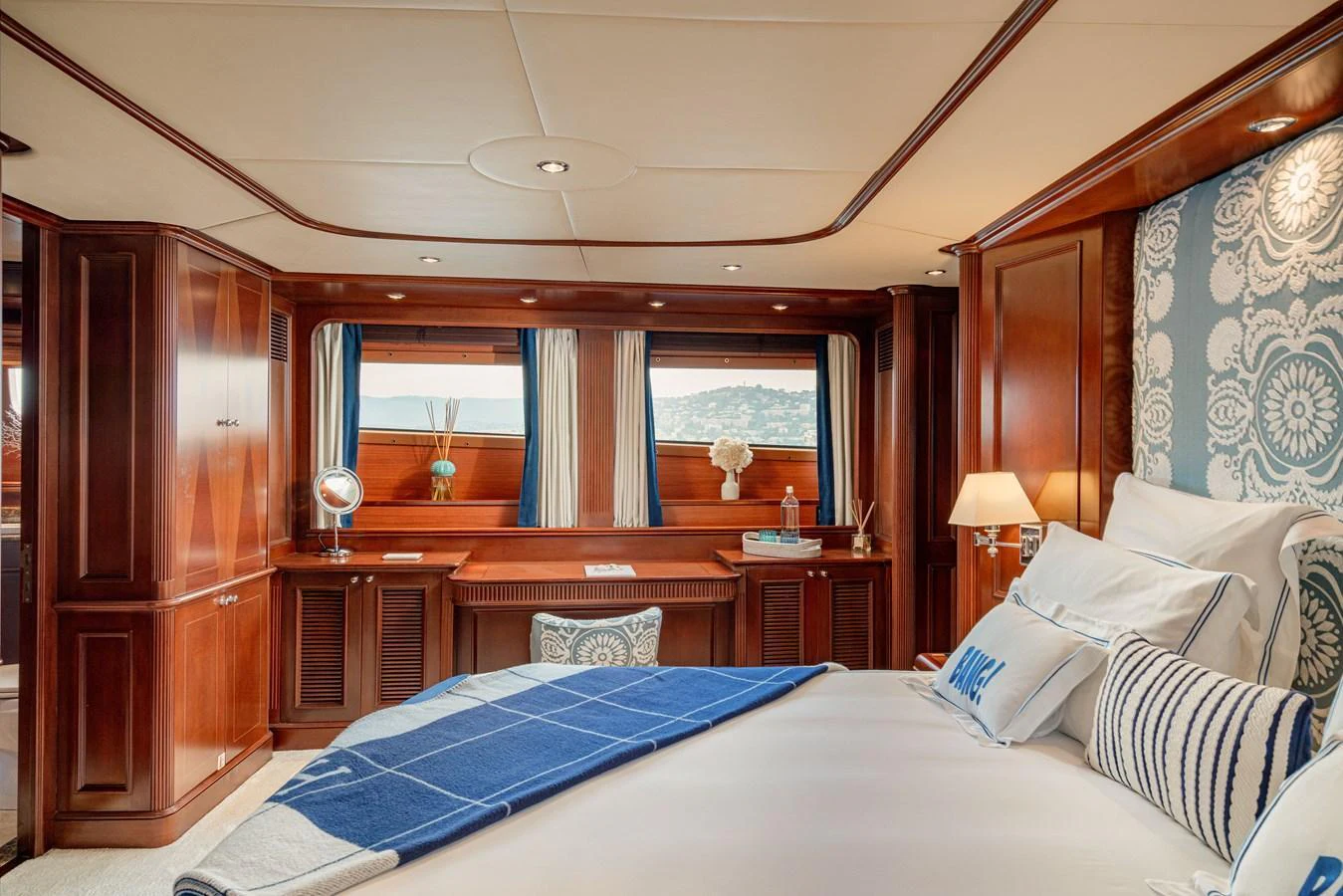 The master stateroom features elegant wood paneling, luxurious bedding, and large windows offering scenic views. aboard BANG! Yacht for Sale