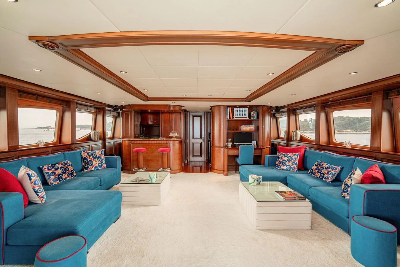 The salon features plush blue seating, wooden accents, and large windows offering panoramic views. aboard BANG! Yacht for Sale