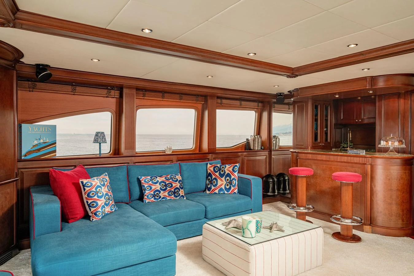 The yacht's salon features a comfortable seating area with a vibrant blue sofa and a stylish bar. aboard BANG! Yacht for Sale