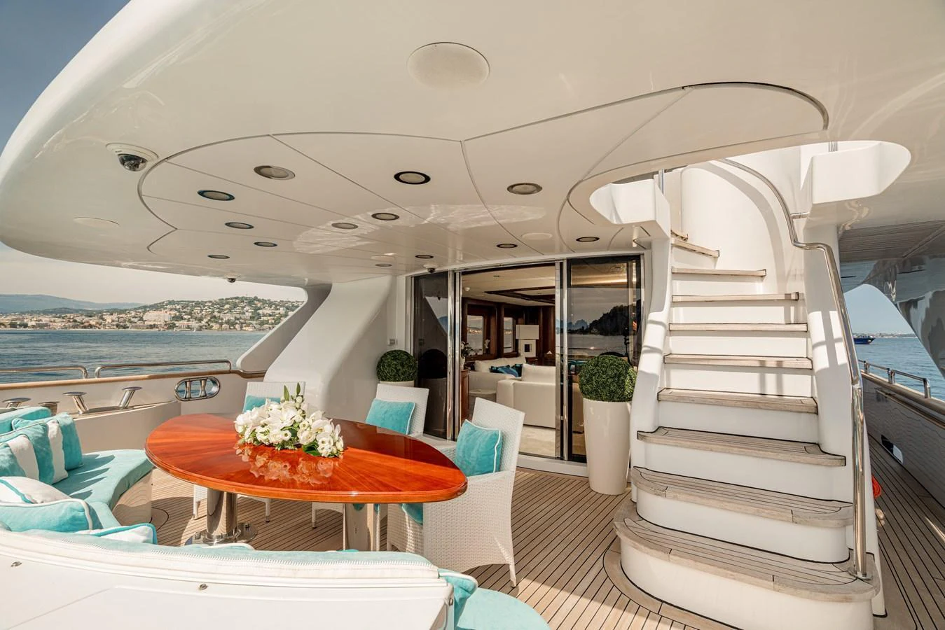 The aft deck features a stylish seating area with a polished wooden table and plush cushions, perfect for alfresco dining. aboard BANG! Yacht for Sale
