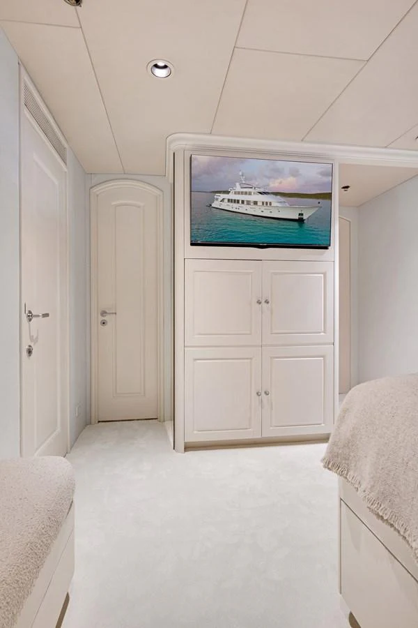 a white room with a television and a white door aboard CHANSON Yacht for Sale