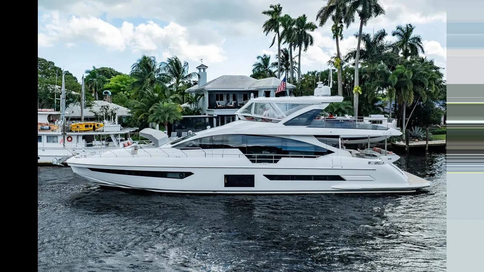 A sleek and modern yacht cruises along a waterfront lined with palm trees and luxurious homes. aboard 2022 AZIMUT GRANDE 25 METRI Yacht for Sale