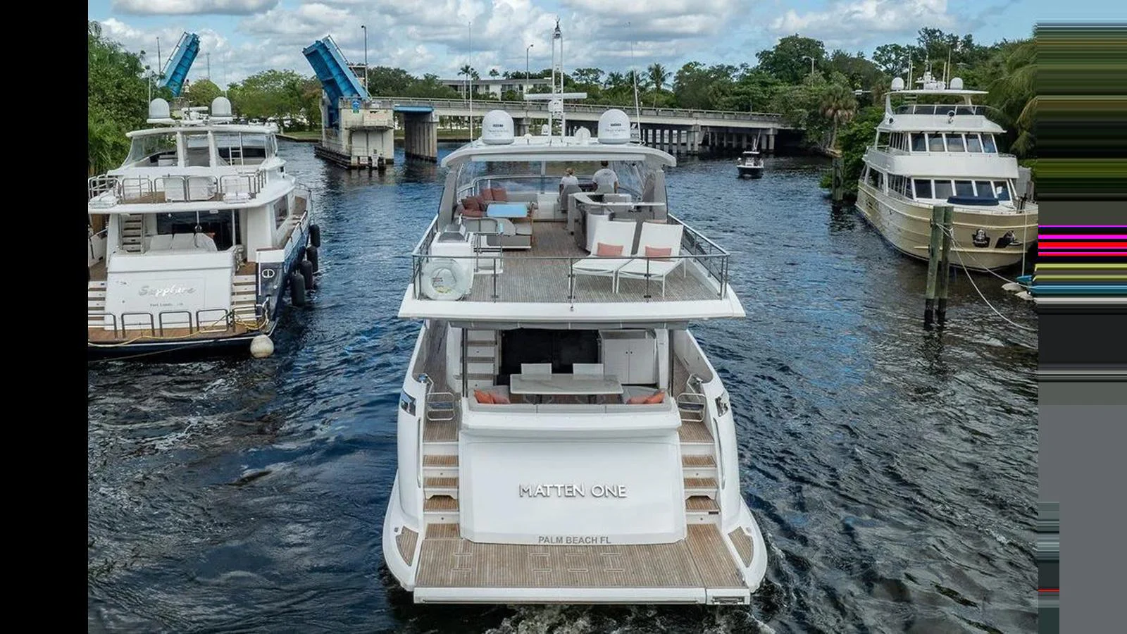 The yacht is seen from the rear, showcasing its spacious aft deck and elegant design as it navigates a waterway. aboard 2022 AZIMUT GRANDE 25 METRI Yacht for Sale