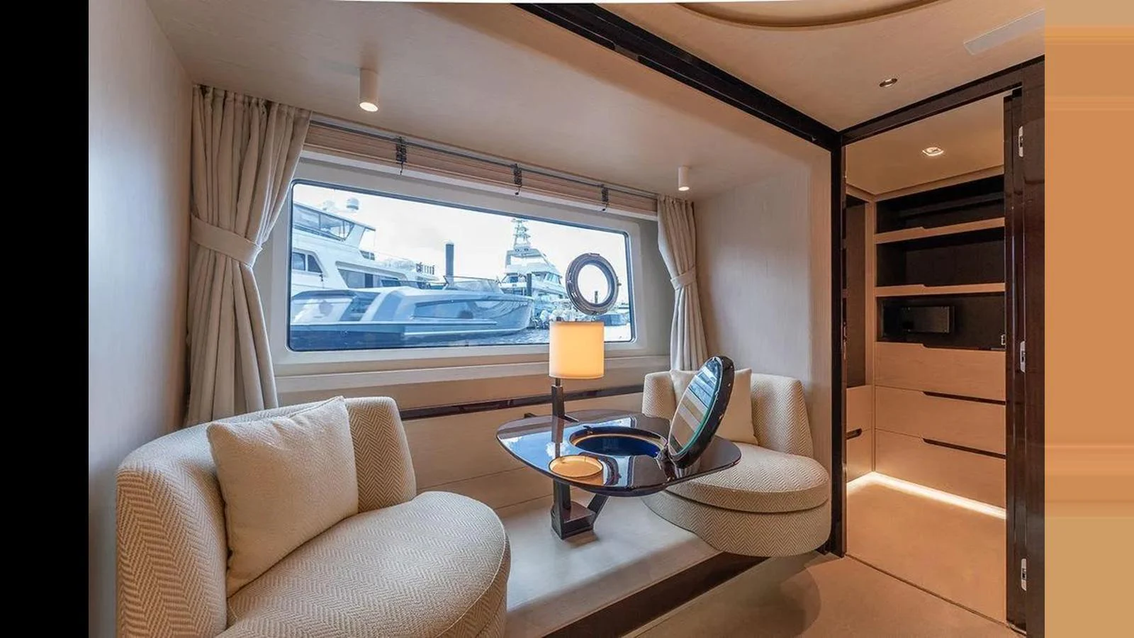 The yacht's interior features a cozy seating area with a large window offering a view of the marina. aboard 2022 AZIMUT GRANDE 25 METRI Yacht for Sale